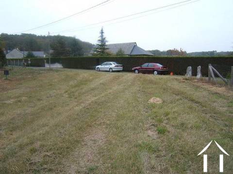 This is a view from midway of the land looking towards to road with the immaculate hedge of the neighbour (our two cars parked in front)