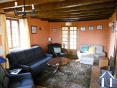The lounge with its exposed oak beams and tiled floor. Seen (bottom right) is the free-standing wood burner.  The internal French doors lead into the dining/kitchen area.