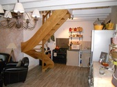The sejour with the simple open plan kitchen at the far end. The hardwood staircase rises to the large mezzanine bedroom and study area.