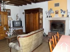 This shows one end of the living room with dining area. The beams and fireplace with its inset wood burning stove can be seen.